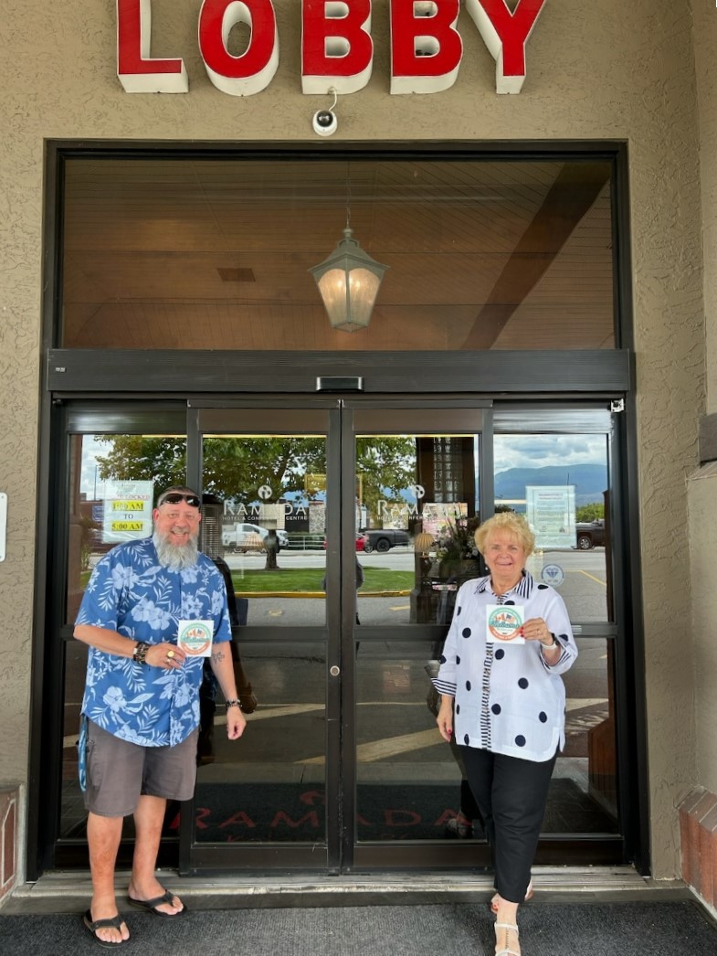 </who>Shane Osborne from the Kelowna Chamber of Commerce and Maxine DeHart from the Ramada Hotel with 'A Warm Welcome' decals.