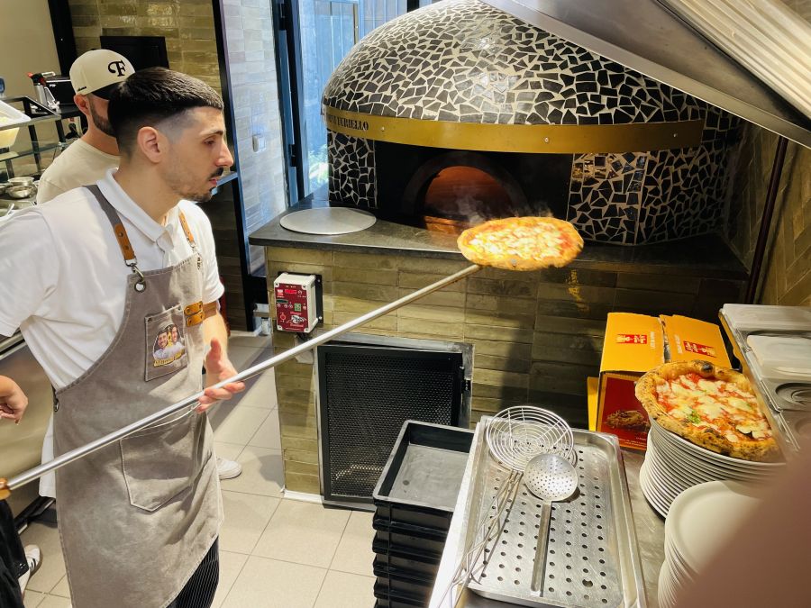 </who>Savio takes a pizza out of the oven, which is fittingly located where the church's altar used to be.