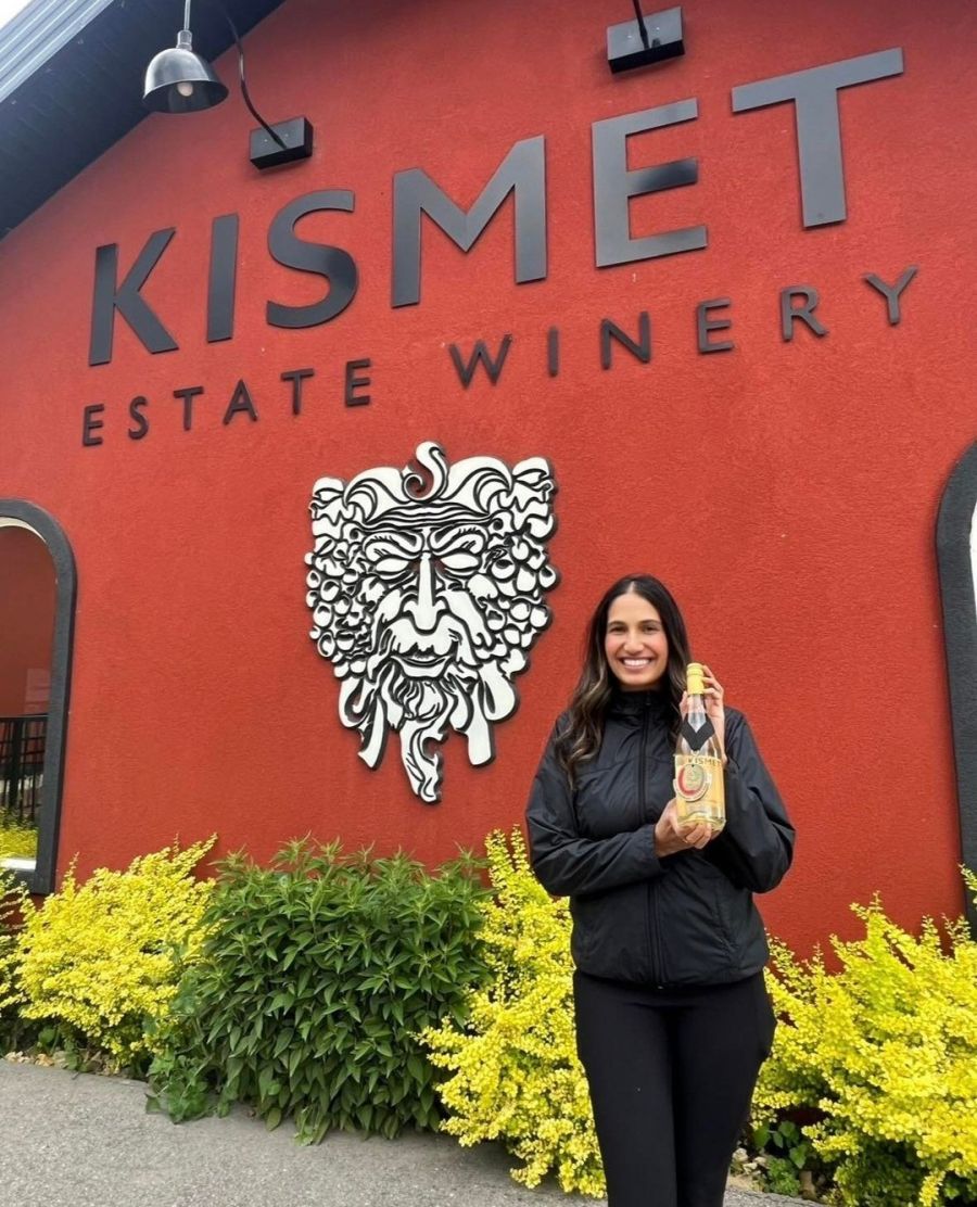 <who>Photo credit: Kismet Winery</who>Kismet winemaker Manpreet with the 2023 Pinot Grigio, which won a double-gold medal at the 2024 All Canadian Wine Championships.