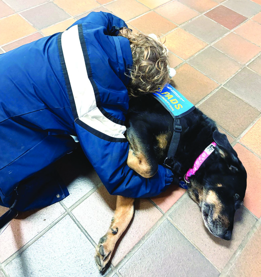 <who> Photo credit: LJI/Penticton Herald </who> The young brother of a boy killed in the Tumbler Ridge mass shooting hugs service dog Benelli during a visit by Penticton crisis intervention worker Dede Dacyk during their recent trip to the small northeastern community.