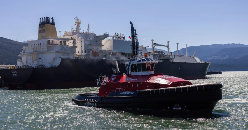<who> Photo credit: Flickr (CC BY-NC-ND 4.0) </who> Tugboats move near an LNG carrier at LNG Canada in Kitimat, BC, during Premier David Eby’s tour of the facility on July 29, 2025.