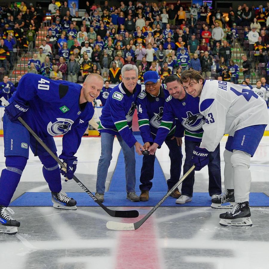 <who>Photo Credit: Vancouver Canucks/Facebook</who>(L to R) Dave Lieskovsky from Kids Sport, Penticton Indian Band Chief Greg Gabril and Penticton Deputy Mayor Campbell Watt drop the puck for a ceremonial faceoff between Elias Pettersson and Quinn Hughes at the Blue vs White scrimmage to wrap up Canucks training camp in 2024.
