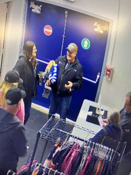 <who>Photo Credit: Trail RCMP</who>Police are trying to identify the man shown in this photo (standing by the door).
